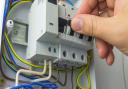 Electrician technician at work on a residential electric panel or electrical switchboard. Electrical fuses, close-up.