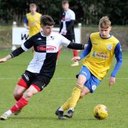 Clevedon Town's Freddie King challenged by former Seasider Callum Gould.