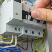Electrician technician at work on a residential electric panel or electrical switchboard. Electrical fuses, close-up.