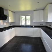 The contemporary kitchen has white gloss units and contrasting worktops